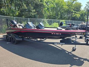 Nitro Z21 2018 Nitro Z21 boat on trailer, parked outdoors, surrounded by trees and fencing.