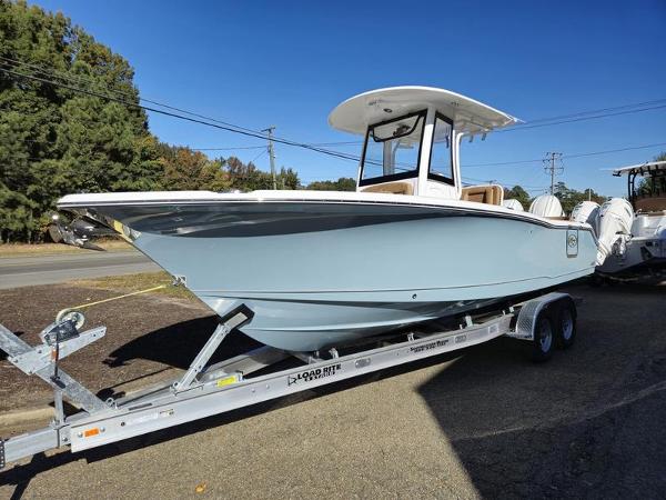 Sea Hunt Ultra 265SE 2025 Sea Hunt Ultra 265SE boat on trailer, parked outdoors under clear blue sky.