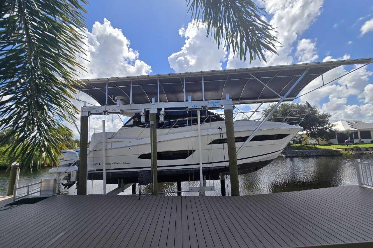 Regal 38 XO 2020 Regal 38 XO yacht on lift, dockside, under blue sky and palm trees.