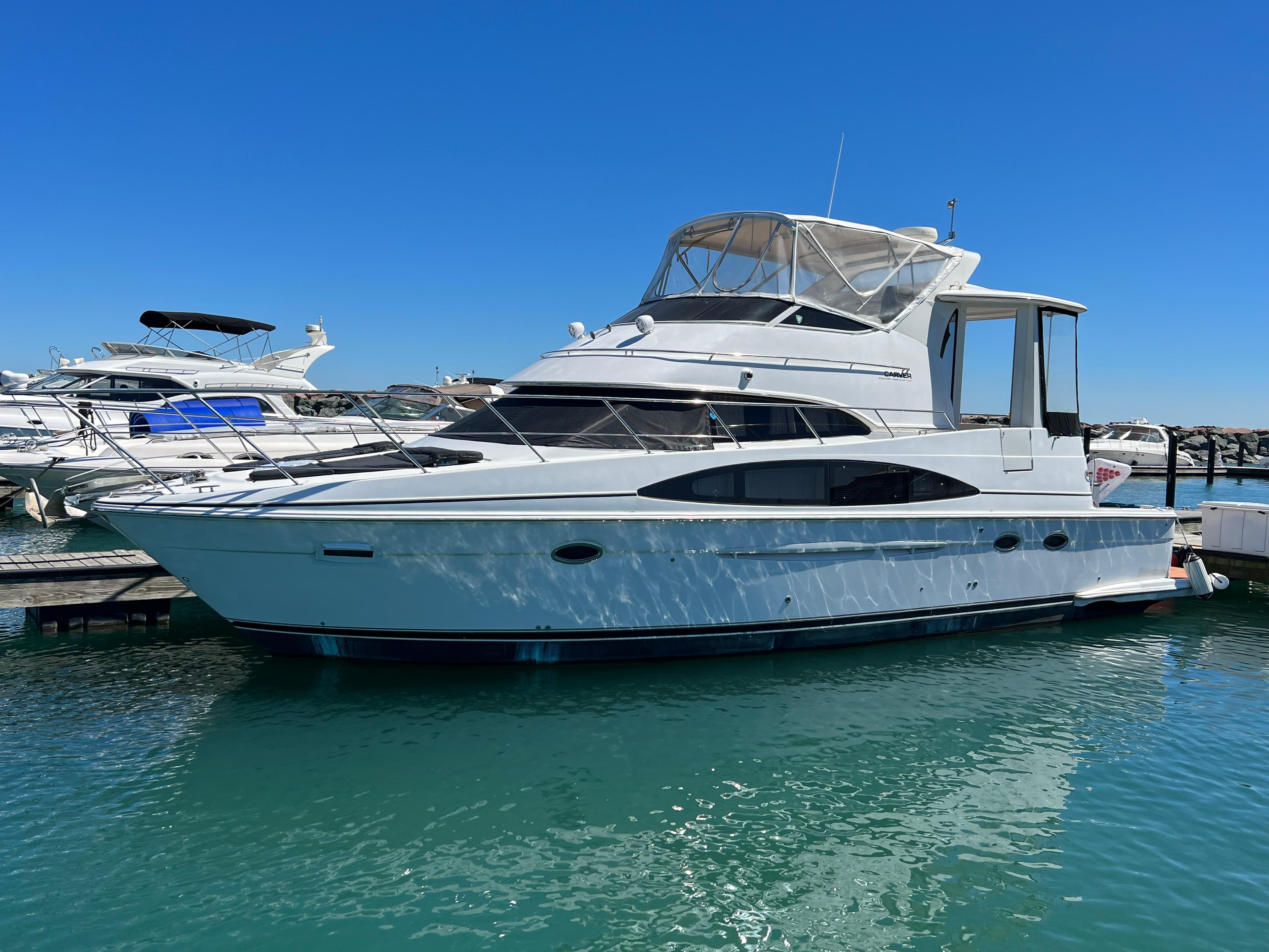 Carver 444 Cockpit Motor Yacht 2002 Carver 444 Cockpit Motor Yacht docked in a marina under clear blue skies.