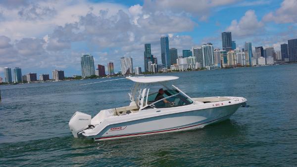 Boston Whaler 240 Vantage 2023 Boston Whaler 240 Vantage boat cruising near city skyline under blue sky.