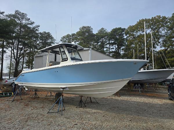 Pursuit S 288 2025 Pursuit S 288 boat in a yard, elevated on stands, surrounded by trees.