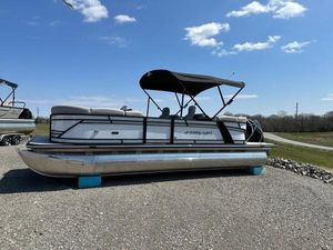 Starcraft SLS 3 2023 Starcraft SLS-3 pontoon boat with canopy on gravel, under a clear blue sky.