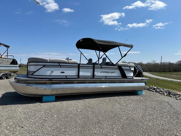 Starcraft SLS-3 2023 Starcraft SLS-3 pontoon boat with canopy on gravel, under a clear blue sky.