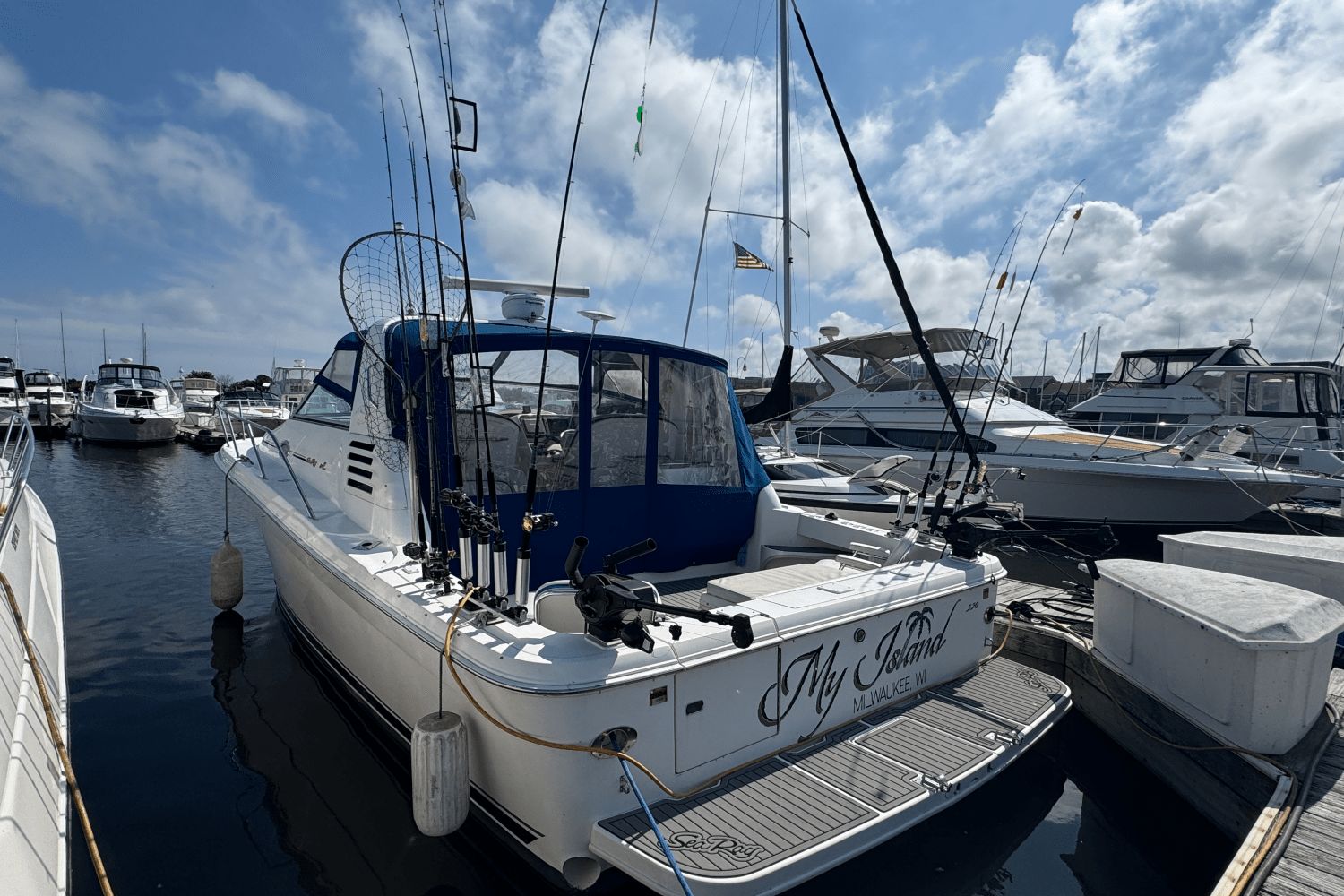 Sea Ray 330 Express Cruiser 1997 Sea Ray 330 Express Cruiser docked with fishing gear, under a partly cloudy sky.
