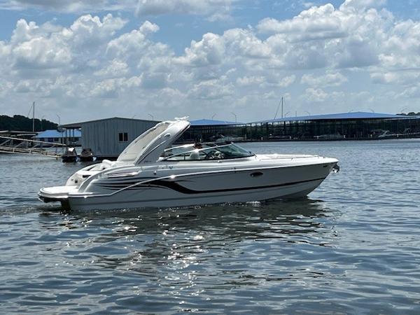 Formula 290 Bowrider 2025 Formula 290 Bowrider boat cruising on a lake near a marina.
