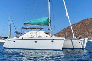 Lagoon TPI 42 1996 Lagoon TPI 42 catamaran sailing on calm waters with a mountainous backdrop.