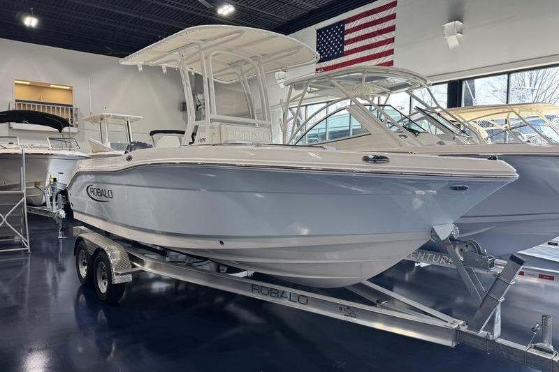 Robalo R 200 CC 2025 Robalo R 200 CC boat on trailer in showroom with American flag.