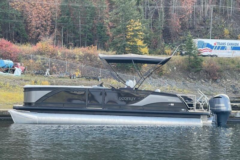Godfrey MC255DFL 2024 Godfrey MC255DFL pontoon boat on a calm lake with autumn foliage backdrop.