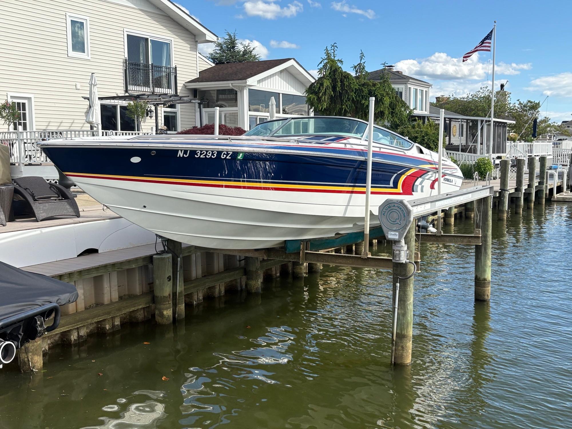 Formula 292 Fast Tech 2006 Formula 292 Fast Tech boat docked by waterfront homes, American flag visible.