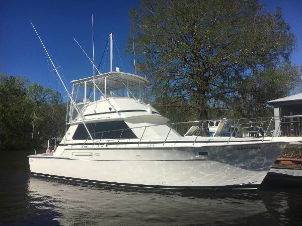 Bertram 42 Convertible 1981 Bertram 45 Convertible yacht on calm water, surrounded by trees.