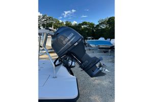 Maverick Hue Outboard motor on a 2005 Tailfisher Hue boat, parked on gravel with trees in background.