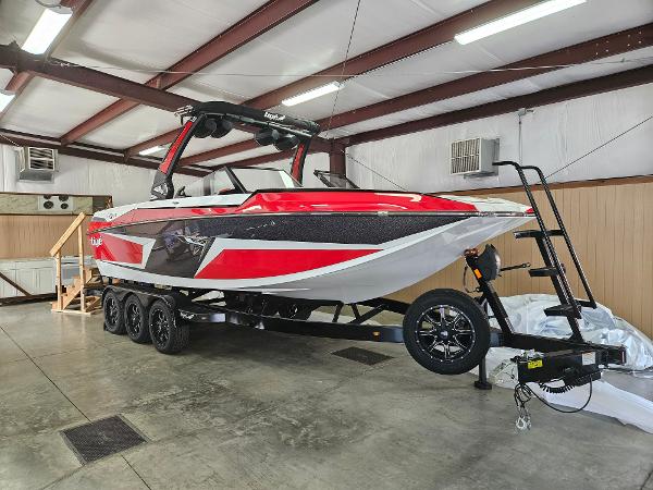 Tigé 24RZX 2024 Tigé 24RZX boat in a storage facility on a trailer.