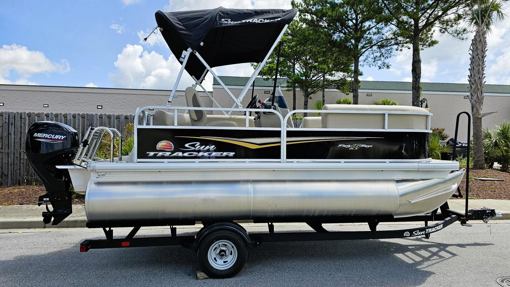 Sun Tracker Party Barge 16 DLX 2025 Sun Tracker Party Barge 16 DLX pontoon boat on trailer, with Mercury outboard motor.