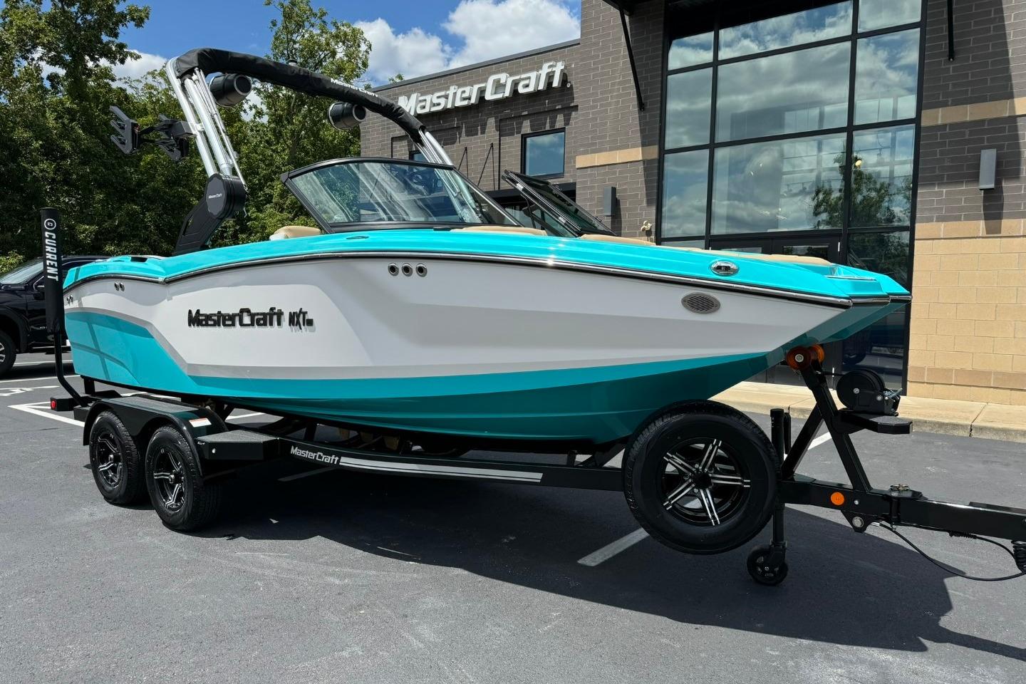 MasterCraft NXT20 2025 MasterCraft NXT20 boat in turquoise and white on a trailer outside dealership.