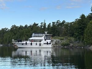 Carver 3608 diesel 1991 Carver 3608 diesel yacht anchored on a serene lake with lush forest backdrop.