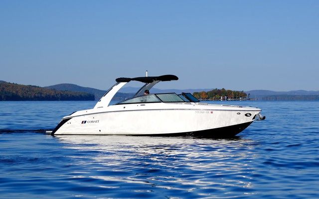 Cobalt R30 2022 Cobalt R30 boat cruising on a serene lake with distant hills.