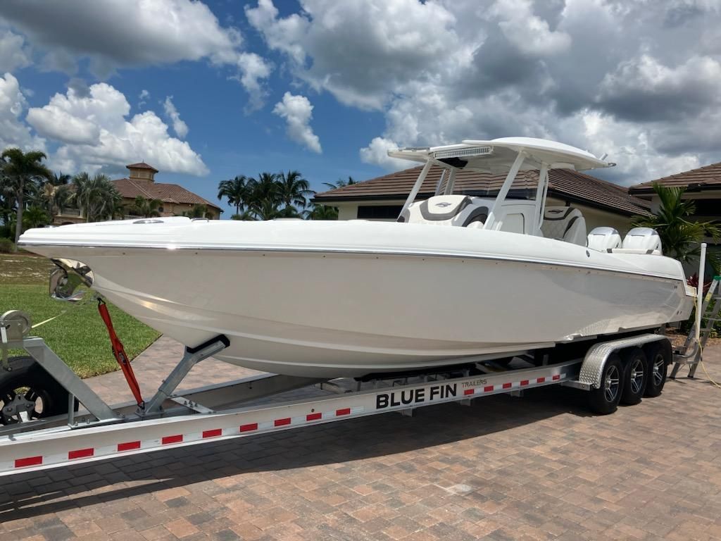 Sunsation 32CCX 2018 Sunsation 32CCX boat on trailer, parked on a driveway under a cloudy sky.