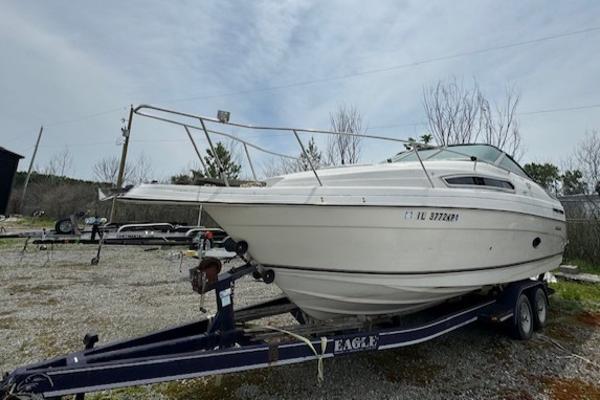 Regal 256 Commodore 1995 Regal 256 Commodore boat on a trailer in a gravel lot.