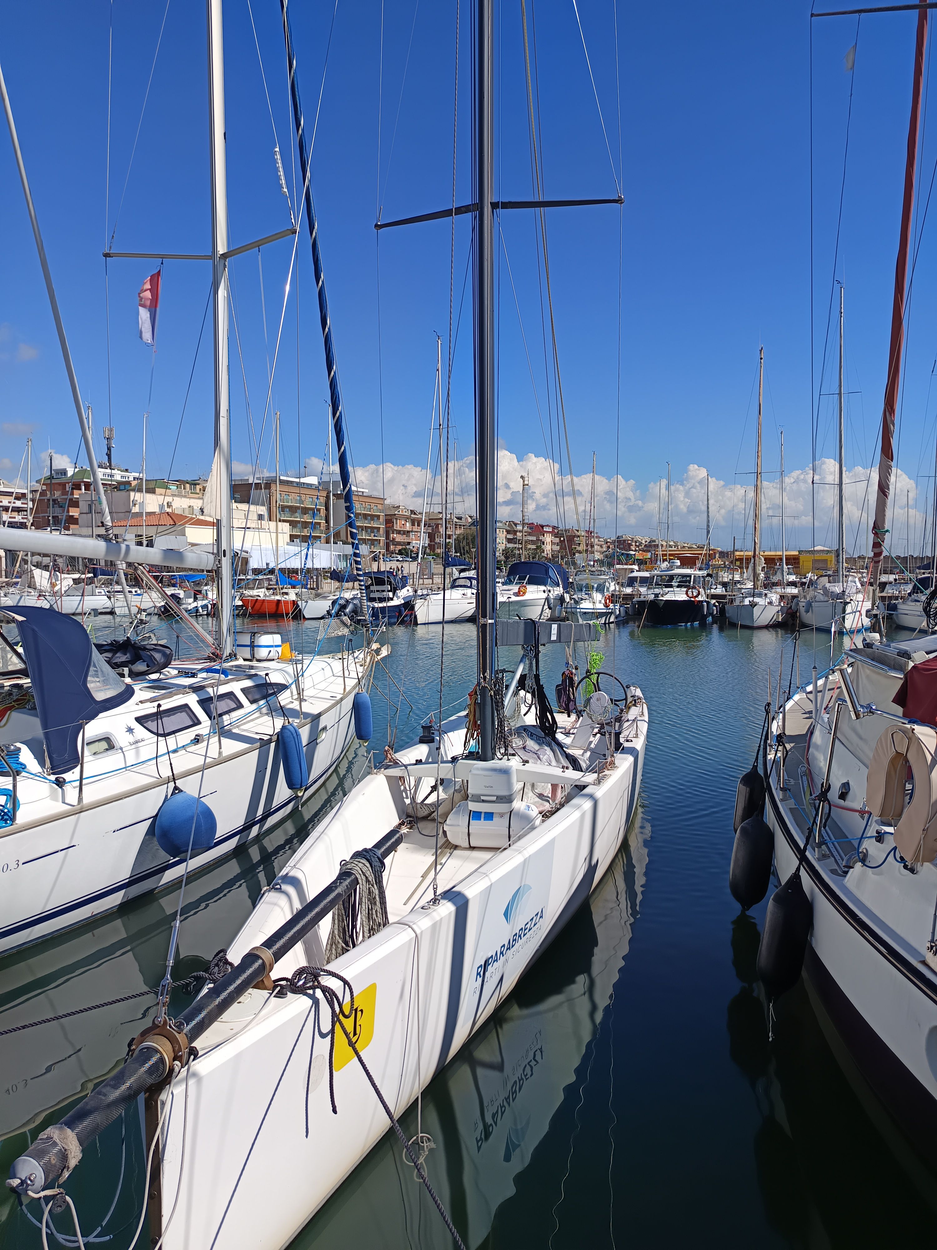 Custom TWELVE OD Sailboats docked in a marina under a clear blue sky, featuring a Custom TWELVE OD model.