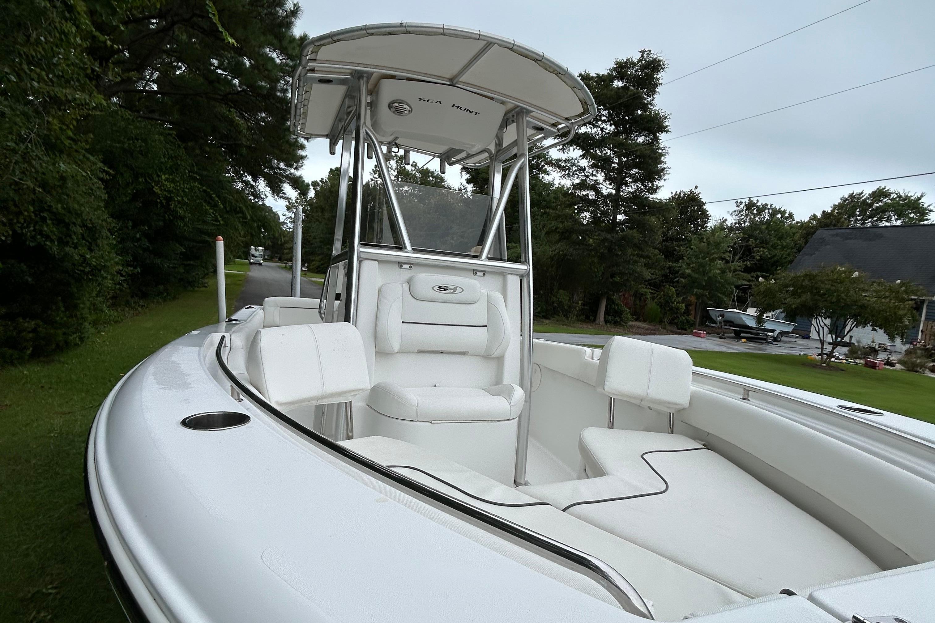 Sea Hunt Ultra 210 2016 Sea Hunt Ultra 210 boat with white seating and T-top, parked on a grassy area.