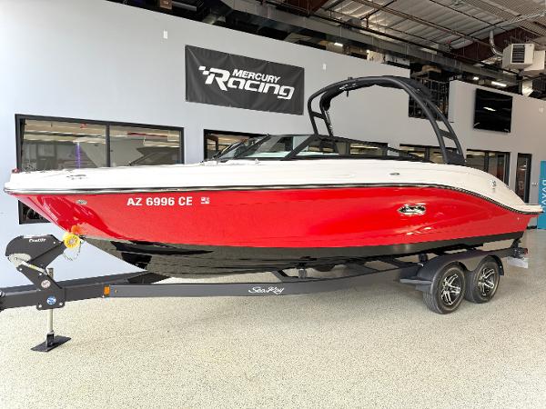 Sea Ray SPX 230 2024 Sea Ray SPX230 boat in showroom, red hull, on trailer, Mercury Racing sign above.
