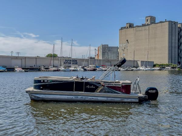 Avalon LSZ 2485 CR 2021 Avalon LSZ 2485 CR pontoon boat on urban waterfront with industrial backdrop.
