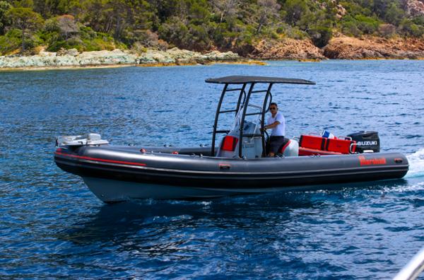 Marshall M6 2021 Marshall M6 boat cruising on blue water near rocky shoreline.