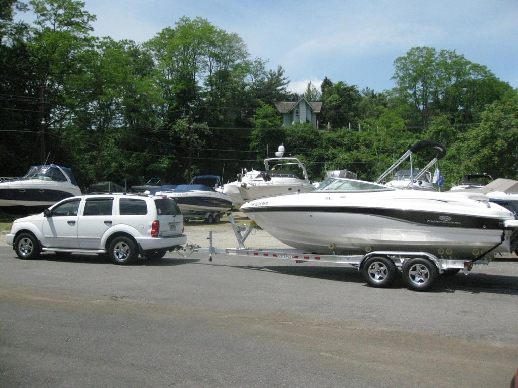 Chaparral 210 SSi White SUV towing 2006 Chaparral 210 SSi boat on trailer, surrounded by trees and other boats.
