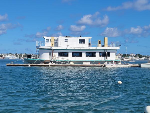 Custom Floating Home Custom 2003 floating home on water, blue sky, and distant boats.