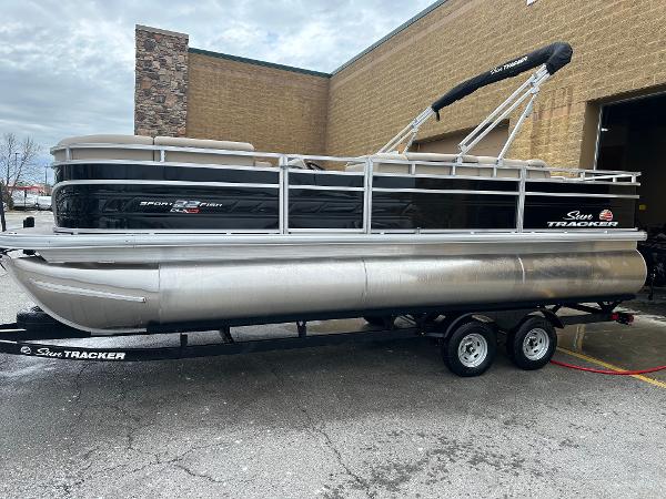 Sun Tracker SportFish 22 XP3 2025 Sun Tracker SportFish 22 XP3 pontoon boat on trailer, parked outside a building.