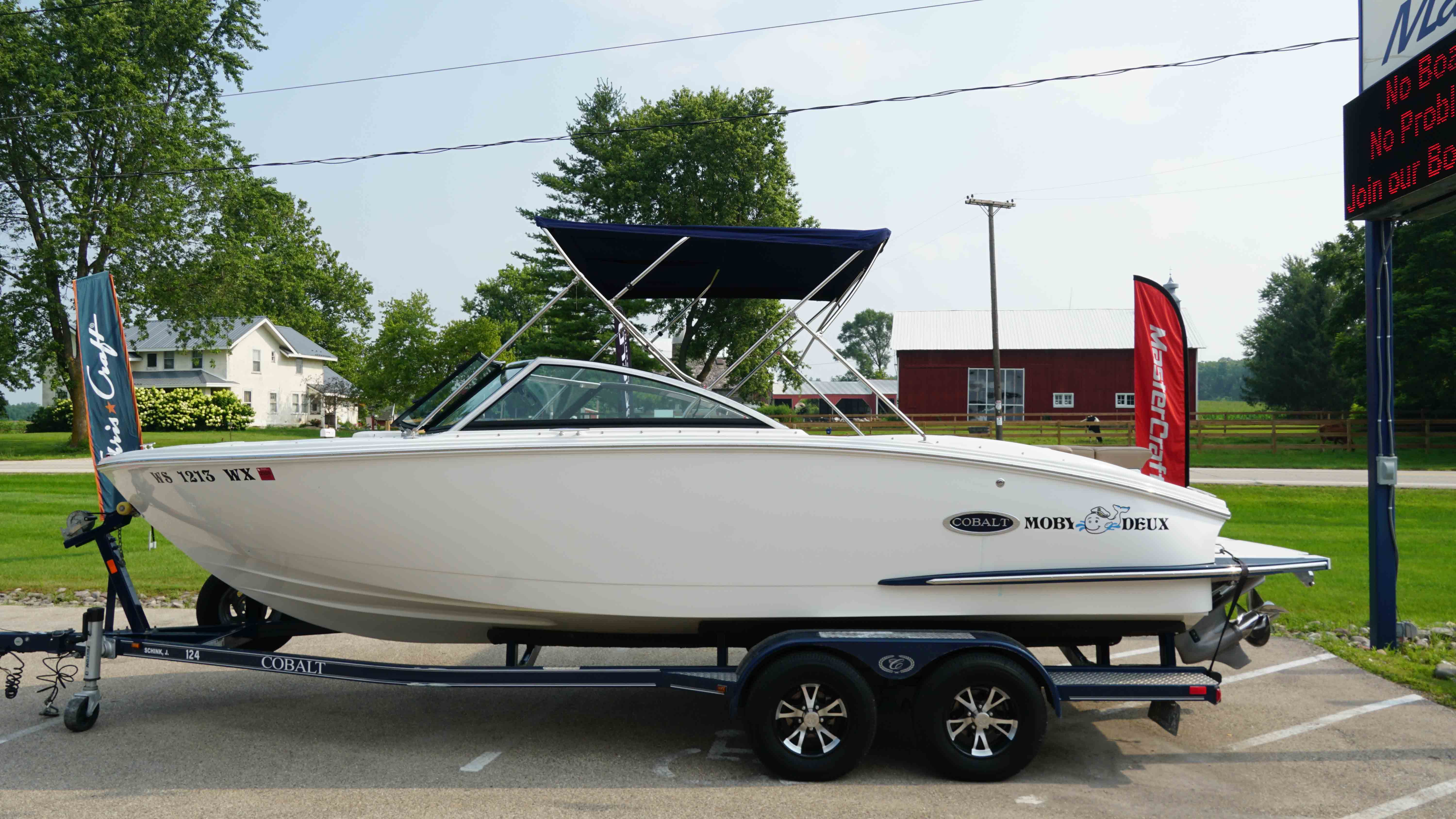 Cobalt CS23 2019 Cobalt CS23 boat on trailer, parked outdoors near trees and buildings.