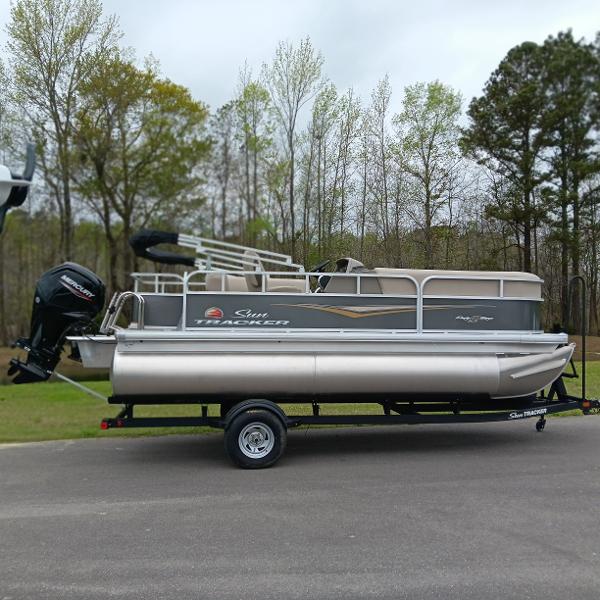 Sun Tracker Party Barge 18 DLX 2025 Sun Tracker Party Barge 18 DLX pontoon boat on trailer, parked outdoors.