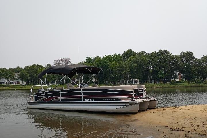 Premier 290 Grand Isle 2013 Premier 290 Grand Isle pontoon boat docked on a sandy shore, surrounded by trees.
