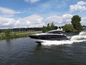 Princess V48 2016 Princess V48 yacht cruising on a scenic river under a partly cloudy sky.