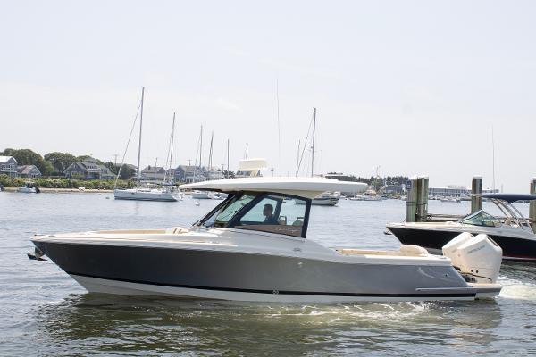Chris-Craft Calypso 32 2025 Chris-Craft Calypso 32 boat cruising in a marina with sailboats in the background.