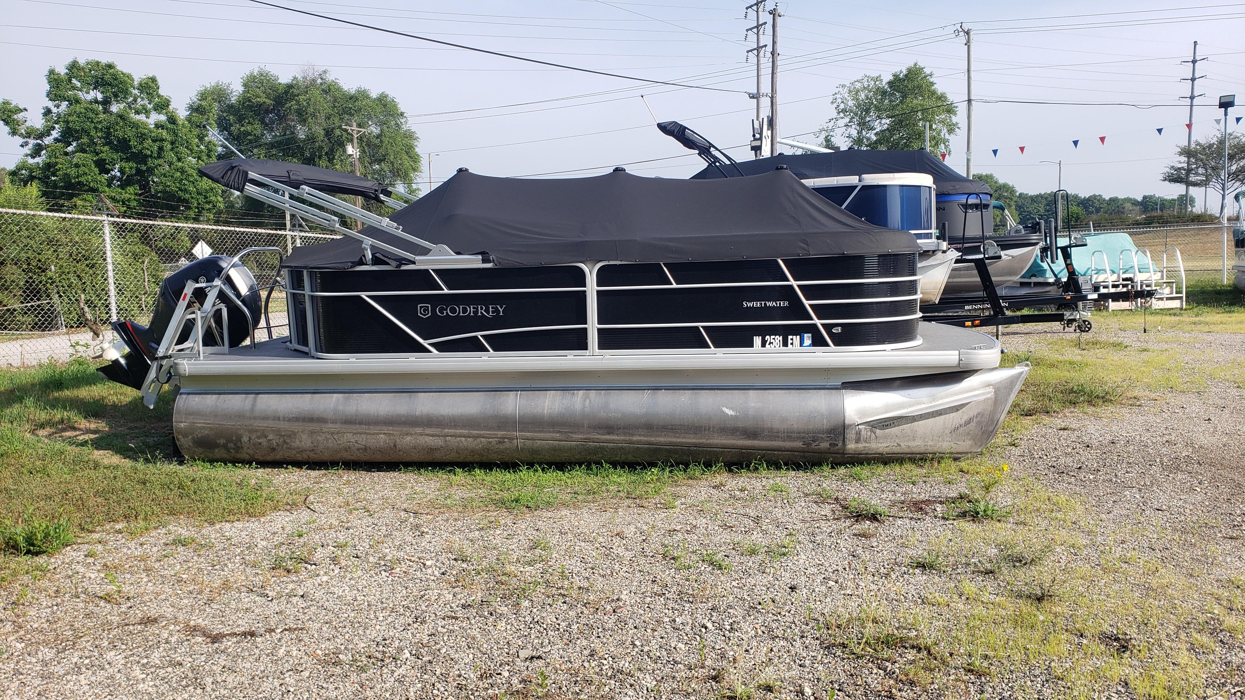 Sweetwater SW2086c 2023 Sweetwater SW2086c pontoon boat with cover, parked on gravel lot.