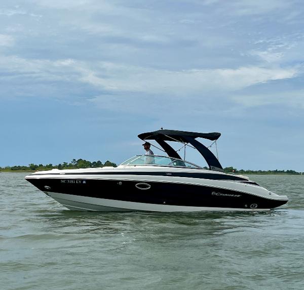 Crownline 275 SS 2017 Crownline 275 SS boat cruising on a calm lake under a partly cloudy sky.