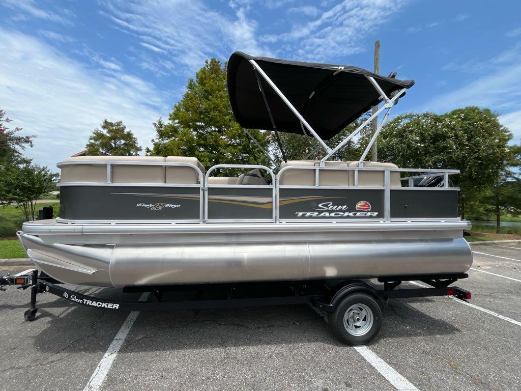 Sun Tracker Party Barge 18 DLX 2025 Sun Tracker Party Barge 18 DLX pontoon boat on trailer, parked outdoors.