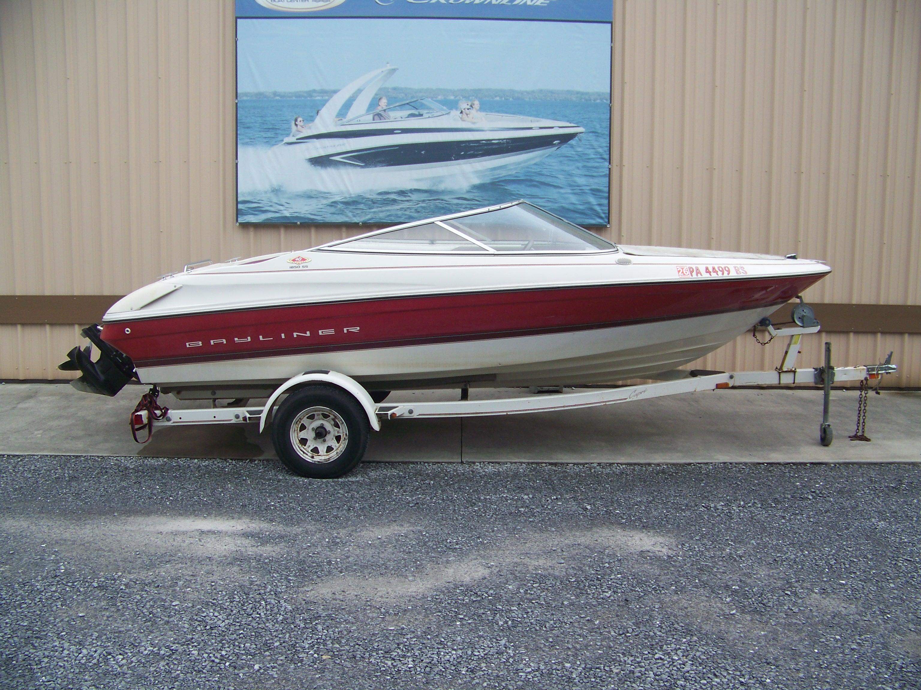Bayliner 1850 Capri Br 1996 Bayliner 1850SS boat on trailer, red and white design, parked outside.