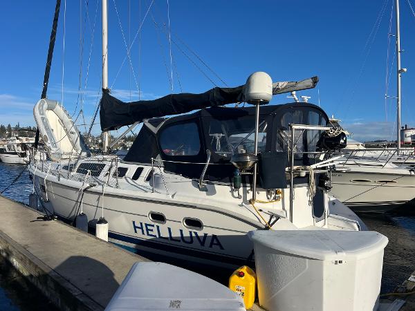 Hunter 410 2000 Hunter 410 sailboat named "Helluva" docked at marina under clear blue sky.