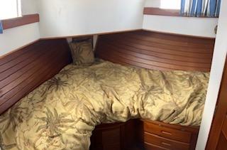 Grand Banks GND01 Cozy cabin bedroom in 1989 Grand Banks GND01 boat with wooden paneling and patterned bedding.