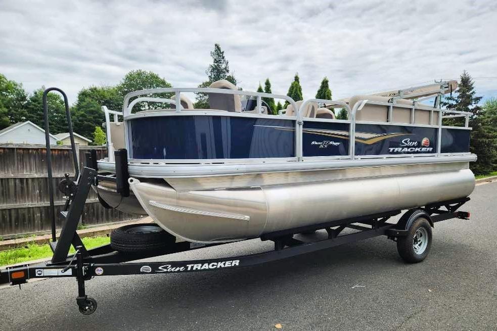 Sun Tracker Bass Buggy 18 DLX 2025 Sun Tracker Bass Buggy 18 DLX pontoon boat on trailer, parked outdoors.