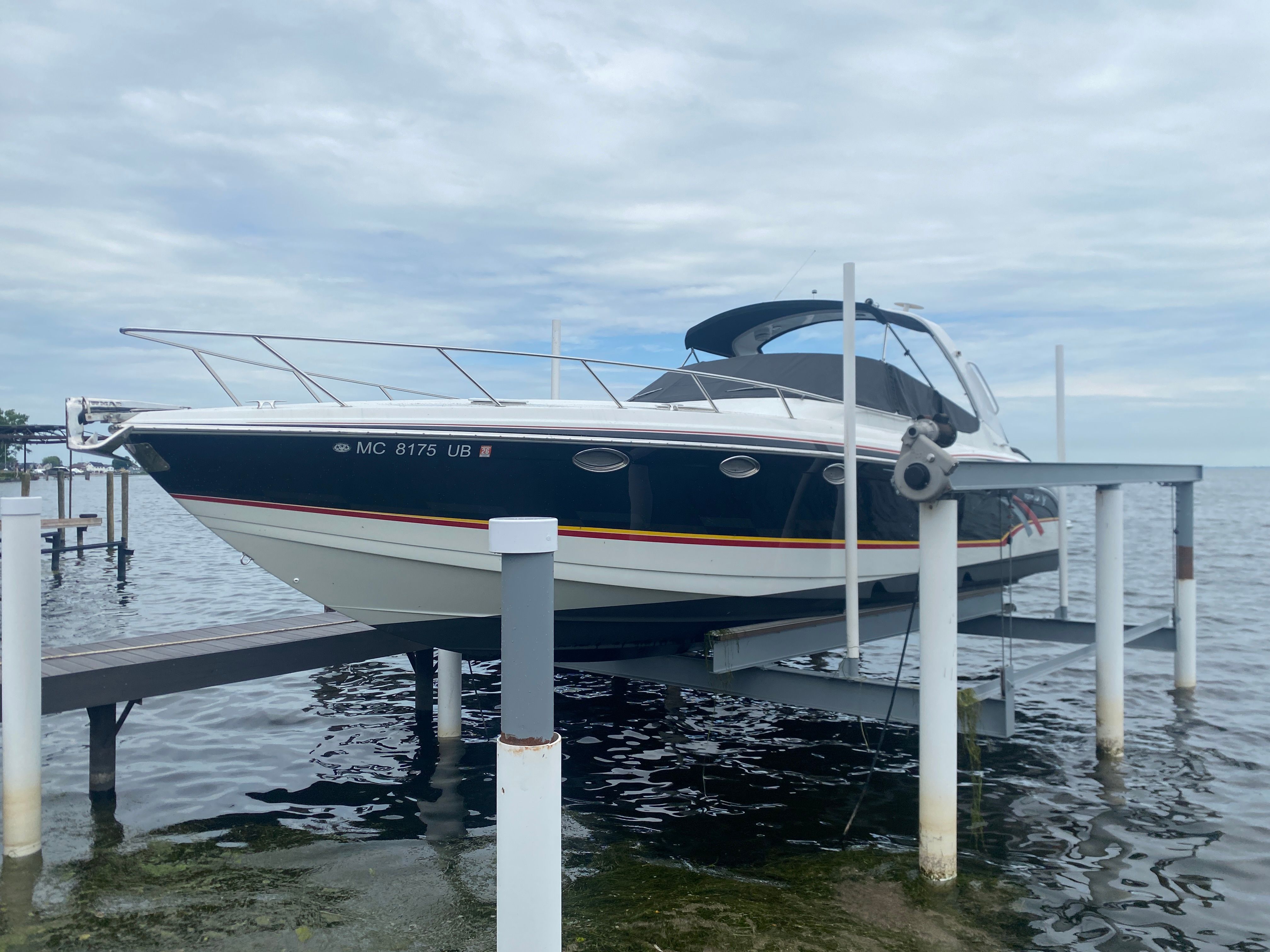 Formula 370 Super Sport 2006 Formula 370 Super Sport boat on lift by the water, under cloudy sky.