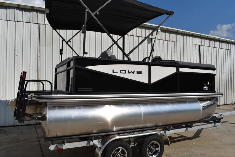 Lowe LS 170 2026 Lowe LS 170 pontoon boat with canopy on trailer, parked by a warehouse.