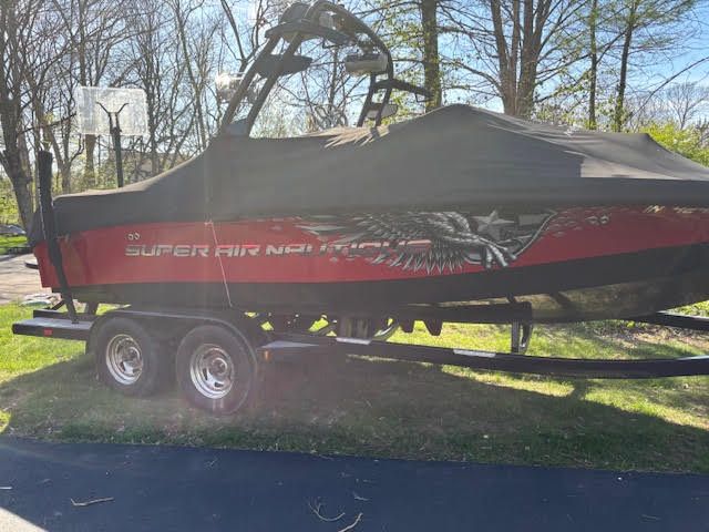 Nautique Super Air Nautique 210 2012 Nautique Super Air Nautique 210 boat with cover on trailer, parked outdoors.