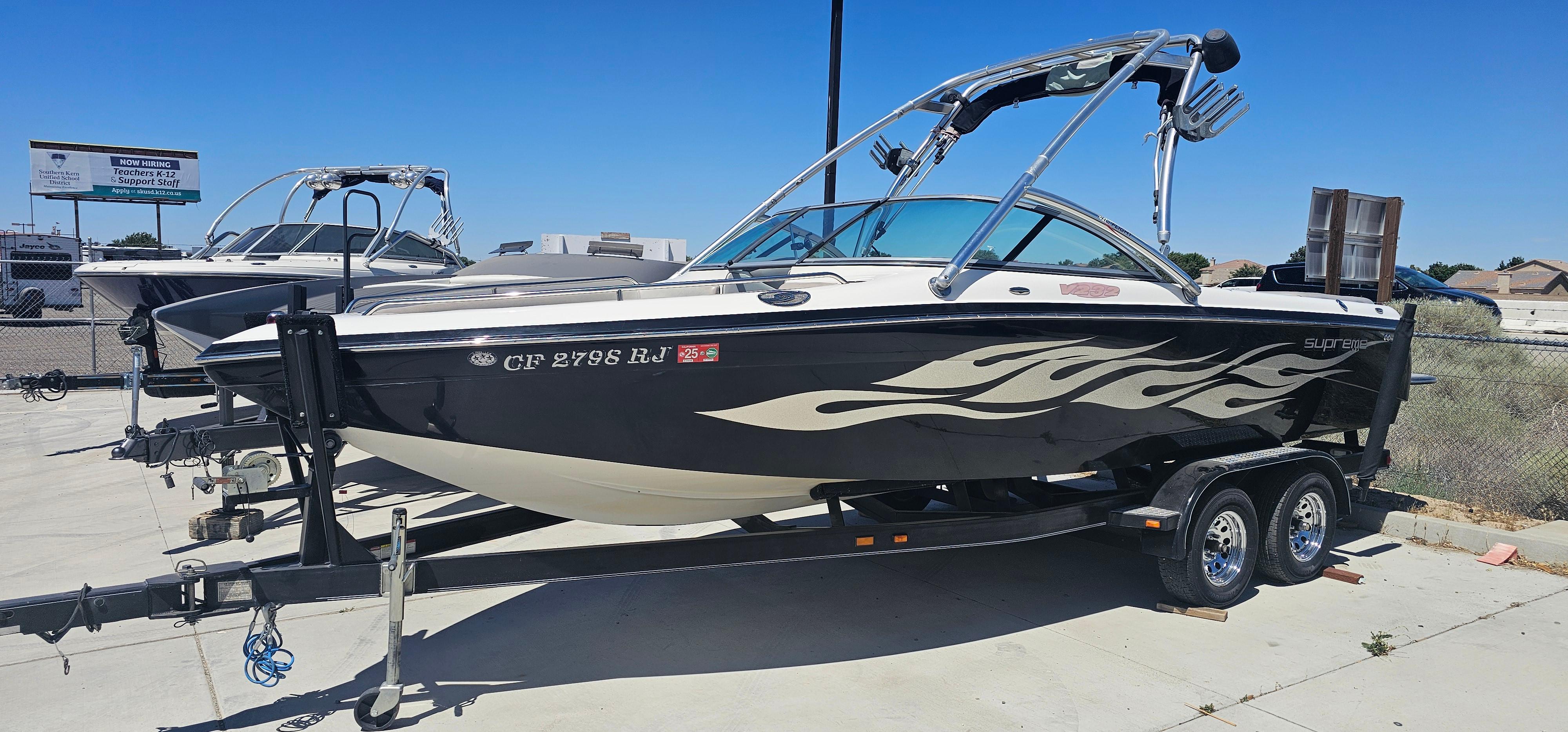 Supreme V232 2007 Supreme V232 boat with flame decals on a trailer, parked outdoors.