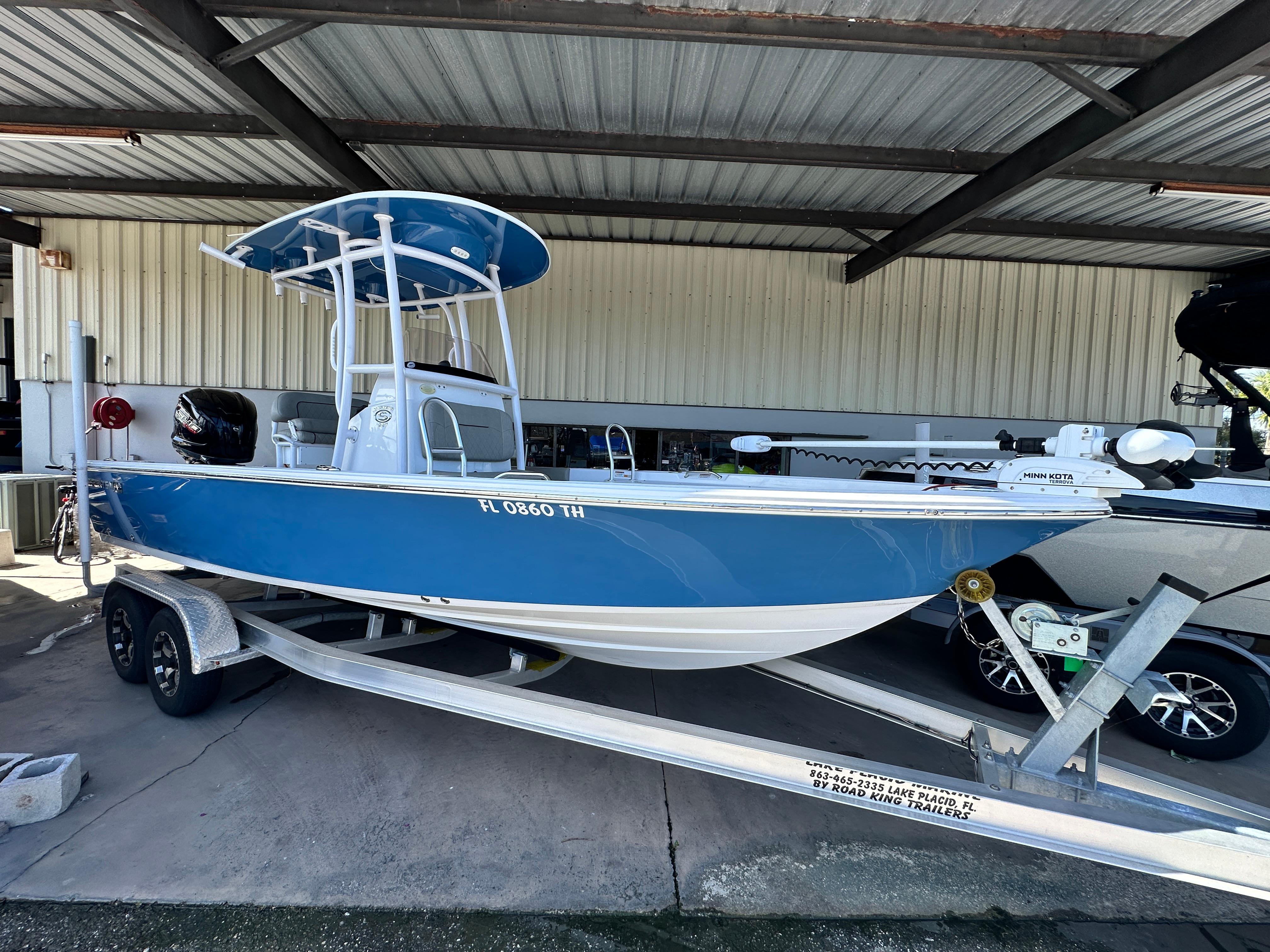 Sportsman Masters 227 Bay Boat 2022 Sportsman Masters 227 Bay Boat in blue on a trailer under a metal roof.