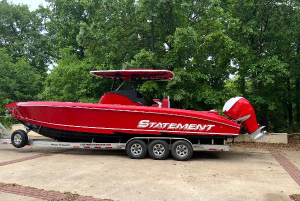 Statement 350 Open Red 2019 Statement 350 Open boat on trailer, parked outdoors with lush green trees.