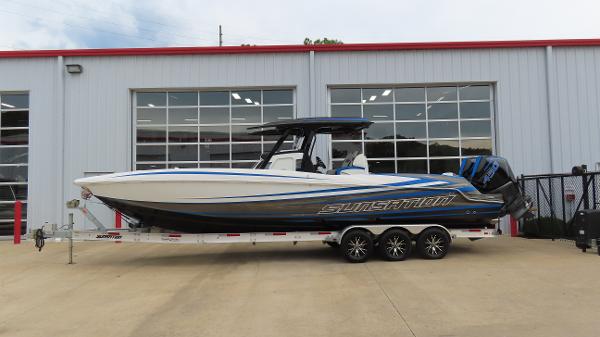 Sunsation 32 CCX 2023 Sunsation 32 CCX boat on trailer outside a garage.